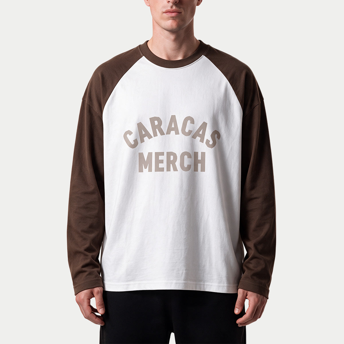 Modelo llevando la camiseta de manga larga varsity blanca y marrón de Caracas Merch